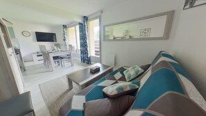 Een moderne woonkamer met een bank, een salontafel, en een eethoek met stoelen en een tafel.