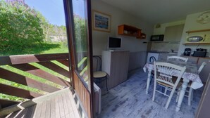 A room with a wooden deck, a small kitchen area, and a dining table with chairs. - Bright studio with loggia and parking in Les Rousses (Les Rousses)