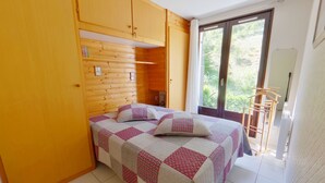 Une chambre à coucher avec un lit, une armoire en bois et une fenêtre donnant sur un paysage verdoyant.