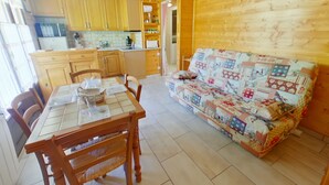 Une cuisine chaleureuse avec des meubles en bois, une table à manger entourée de chaises et un canapé aux couleurs vives.