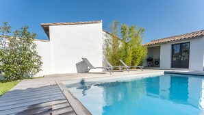 A swimming pool with a wooden deck, lounge chairs, and a small building with a tiled roof. - Family house for 10 with patio and pool in La Flotte (La Flotte)