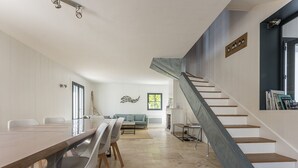 A spacious living area with a long wooden table and chairs, a staircase with a metal railing, and a view of the outdoors through a window. - Family house for 10 with patio and pool in La Flotte (La Flotte)