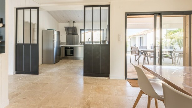 A modern kitchen with a central island, a dining area with a large table and chairs, and a view of the outdoors through a glass door. - Family house for 10 with patio and pool in La Flotte (La Flotte)