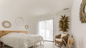 A bedroom with a bed, a wicker chair, and a large window. - 125m² Villa with Heated Pool, 3 Bedrooms, Terrace in La Flotte (La Flotte)