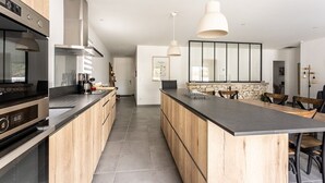 A modern kitchen with wooden cabinets, a central island, and pendant lighting. - 125m² Villa with Heated Pool, 3 Bedrooms, Terrace in La Flotte (La Flotte)