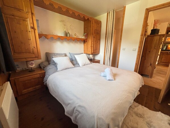 A bedroom with a large bed, wooden headboard, bedside tables, a mirror, and a wardrobe.
