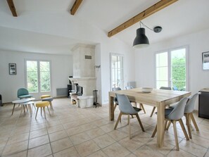 Eine geräumige Küche mit einem großen Holztisch, grauen Stühlen und einer schwarzen Pendelleuchte.