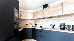 Una cocina moderna con armarios oscuros, encimera de madera y piso de baldosas.