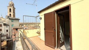 A residential building with a balcony, a brown shutter door, and a visible tower in the background. - O03 – Osimo, One-Bedroom Apartment with Terrace and Wi-Fi (Osimo)