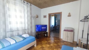 A room with a bed, a television, a dining area, and a wardrobe. - Ferien_Haus & Groß Grundstück in Bad Elster (Bad Elster)