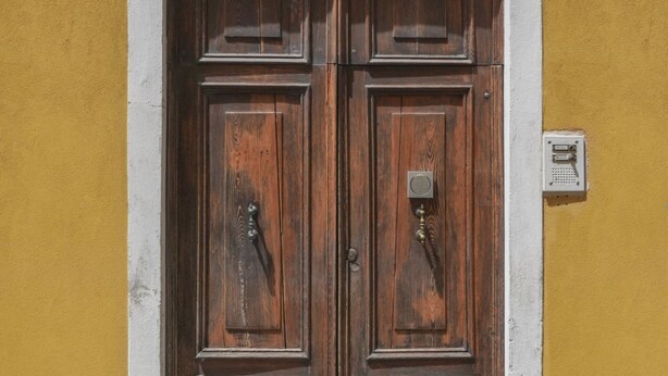 Une porte à deux battants en bois, de style traditionnel, encadrée dans un mur jaune.