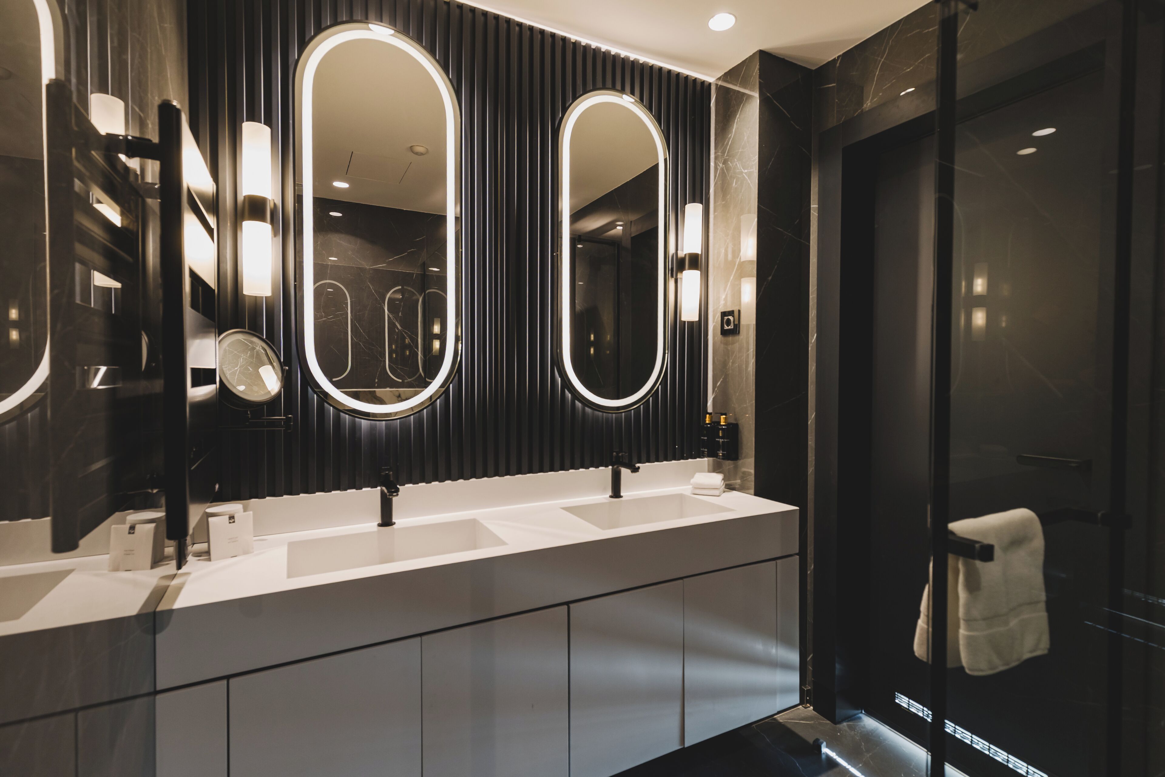 A modern bathroom with a double sink, large mirrors, and a glass shower enclosure.