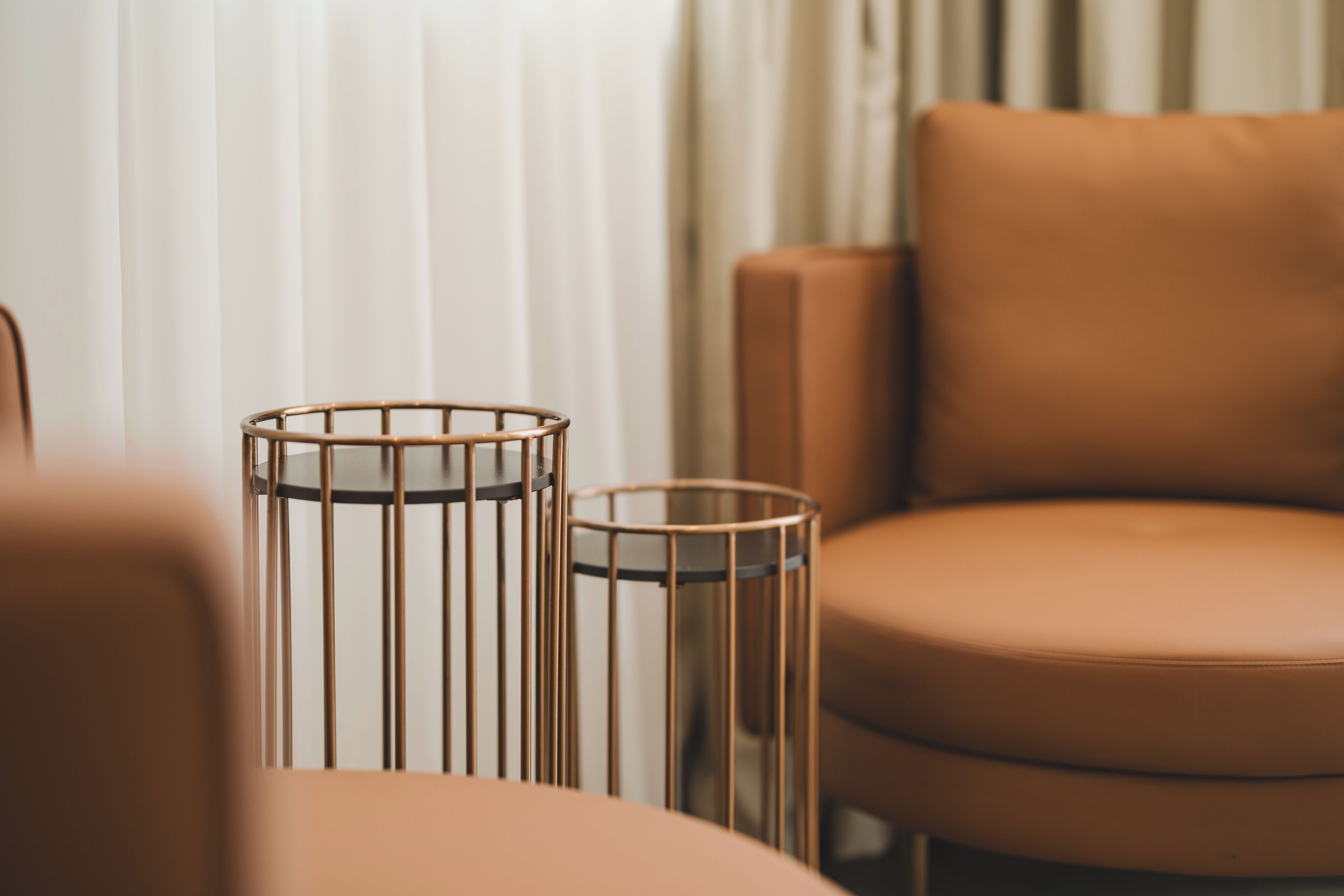 Primer plano de una habitación con un sillón de cuero marrón y una mesita auxiliar de metal.