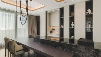 A modern dining area with a marble table, cushioned chairs, and built-in shelving with decorative items.
