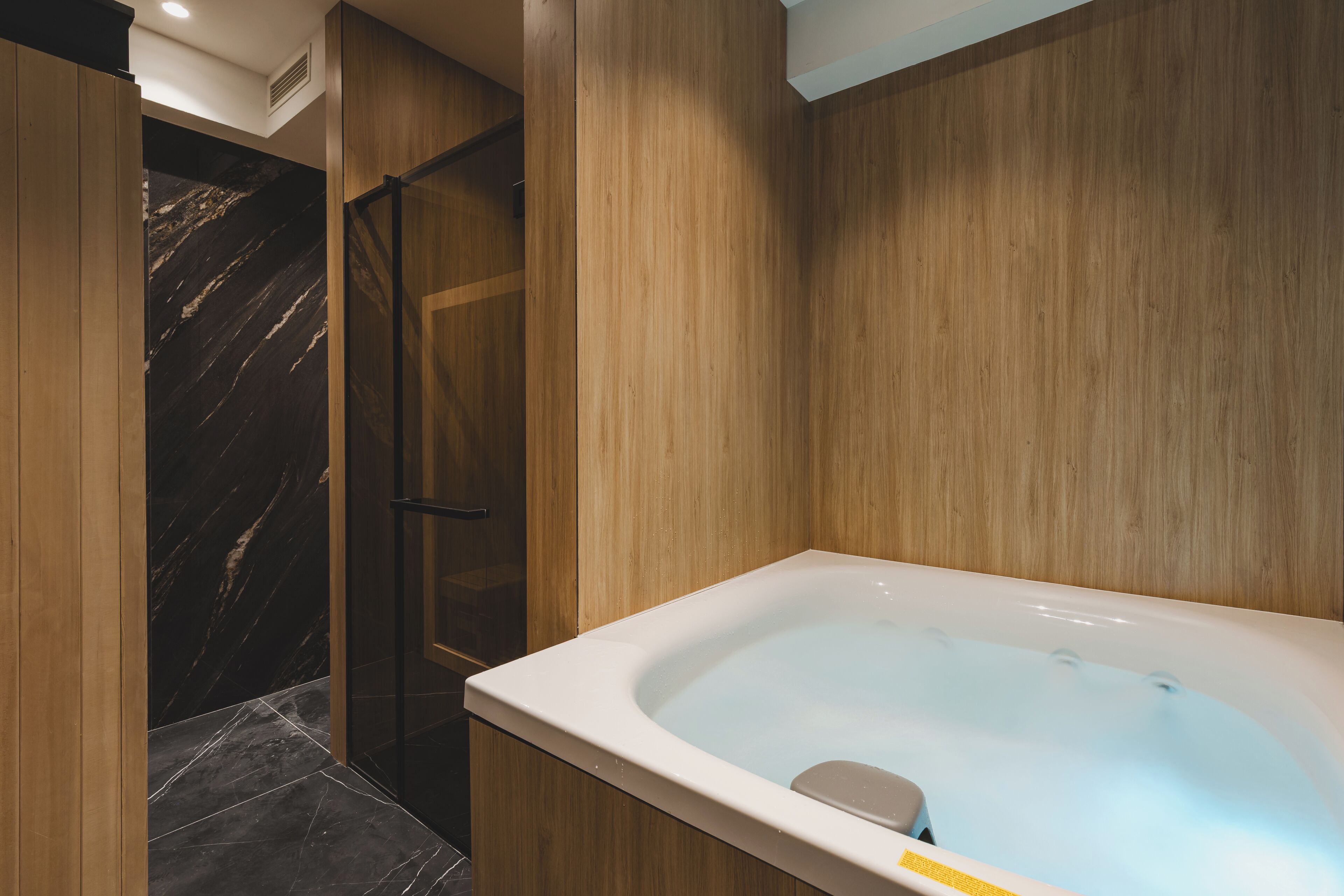 Une salle de bain moderne avec une douche en marbre, un meuble-lavabo en bois et une baignoire sur pieds.