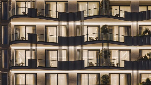 Ein mehrstöckiges Hotel mit Balkonen, großen Fenstern und Außenbereichen mit Sitzgelegenheiten.