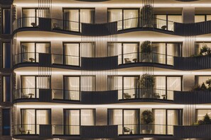 Un hôtel à plusieurs étages doté de balcons, de grandes fenêtres et d’espaces extérieurs aménagés pour s’asseoir.