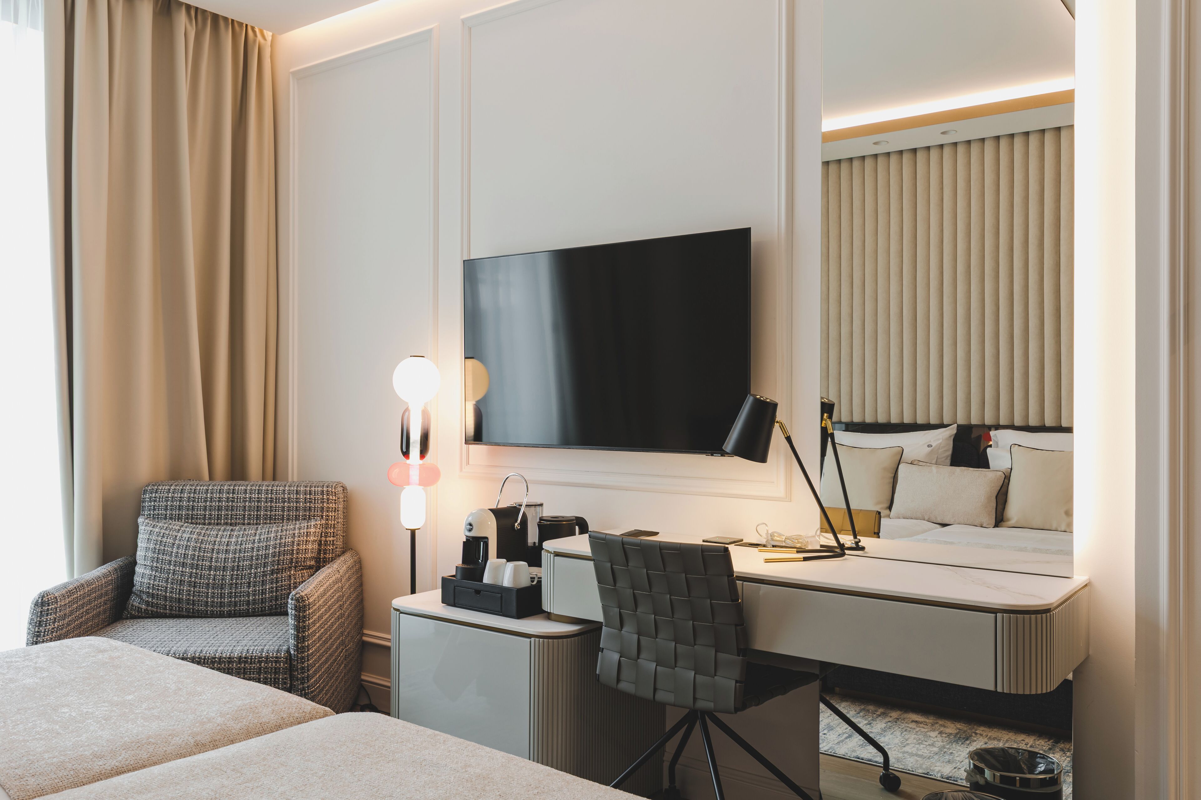 Et hotelværelse med en seng, et skrivebord med en computer, en stol, et fjernsyn og en lampe.