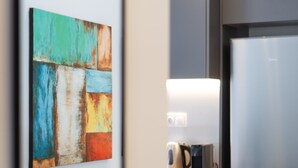 Une cuisine moderne équipée d’un réfrigérateur en acier inoxydable, d’une machine à café et d’un four à micro-ondes posés sur le plan de travail.