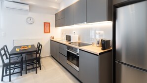Une cuisine moderne avec des meubles gris, un réfrigérateur en acier inoxydable, un four à micro-ondes et un four encastré.