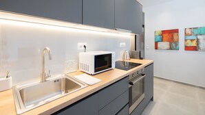Une cuisine moderne dotée d’un évier en acier inoxydable, d’un four à micro-ondes blanc et d’un four encastré.
