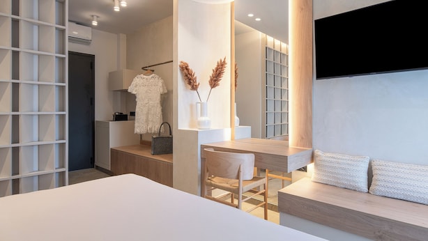 A modern bedroom with a large bed, a bedside table, a mirror, and a wardrobe. - Olenia Suites (Neos Marmaras)