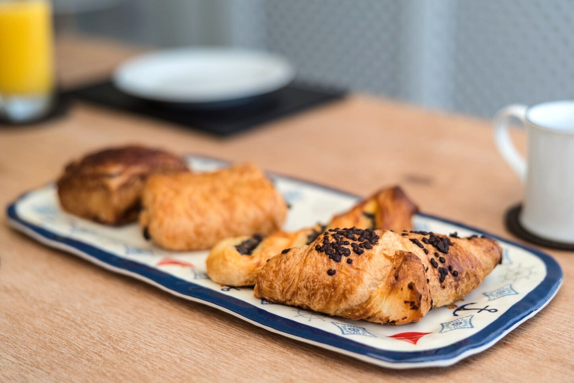 Ein Teller mit Croissants und eine Tasse Kaffee auf einem Holztisch.