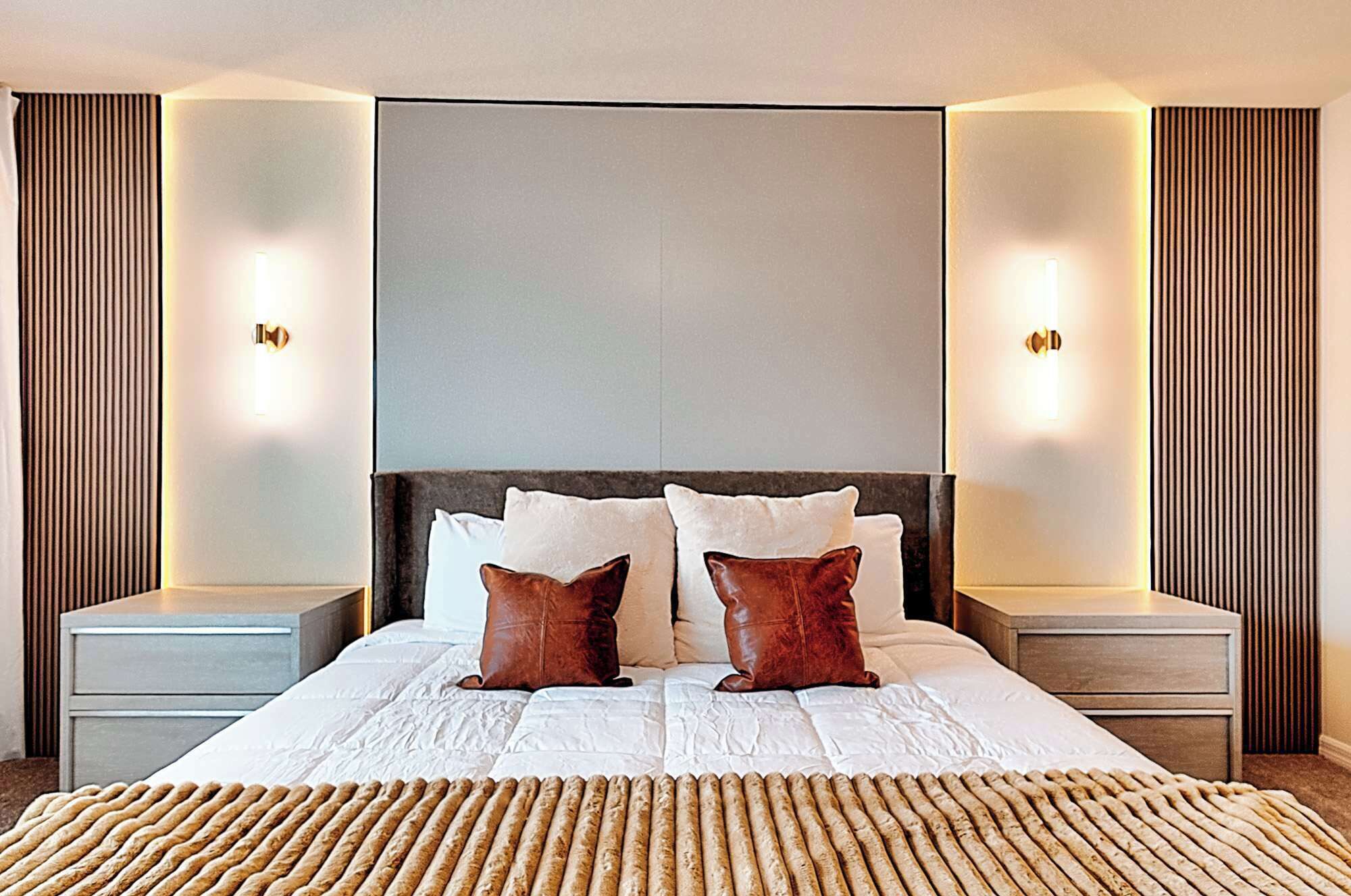 A modern hotel room with a large bed, two nightstands, and wall-mounted lighting.