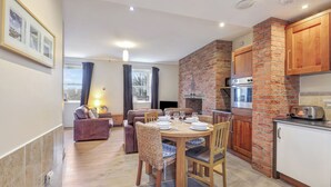A modern kitchen with a brick wall, wooden cabinets, and a dining area with a table set for four.