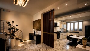 A modern kitchen with a central island, a dining area with a table and chairs, and a staircase leading to another level.
