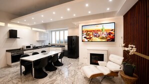 A modern kitchen with a dining area, a fireplace, and a large TV mounted on the wall.