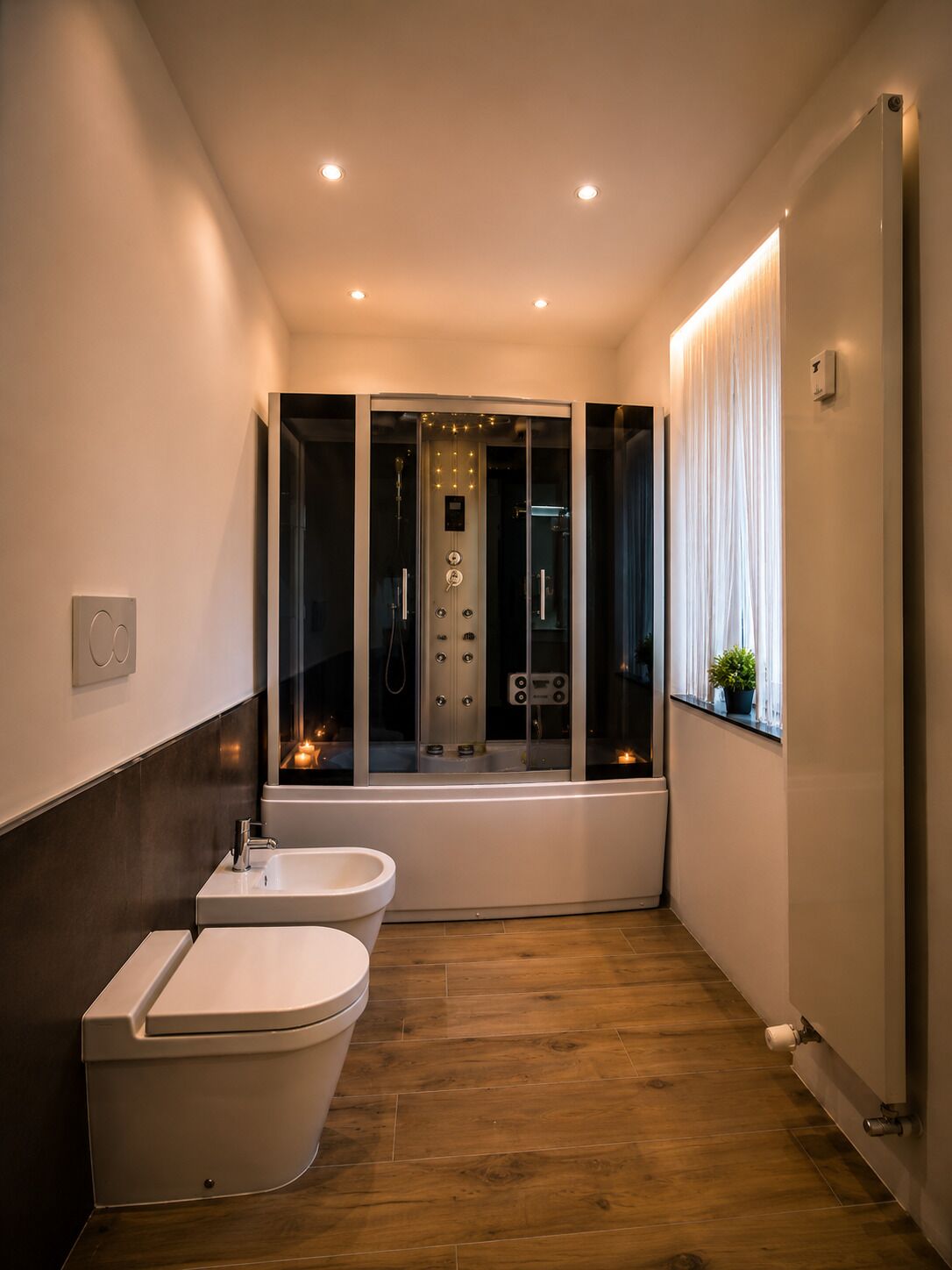 Une salle de bain moderne avec une baignoire, deux toilettes et un espace de douche séparé par des parois en verre.