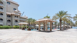 A spacious outdoor area with a pool, palm trees, and a building with balconies.