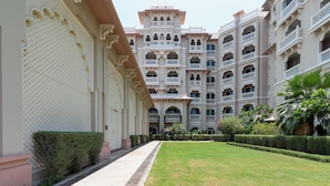 A courtyard with a pathway leading to a building with multiple balconies and a central archway.