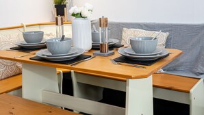 A compact dining area with a wooden table set for two, featuring grey bowls and plates. - Relaxing 4BR Near City Centre  (Salford)