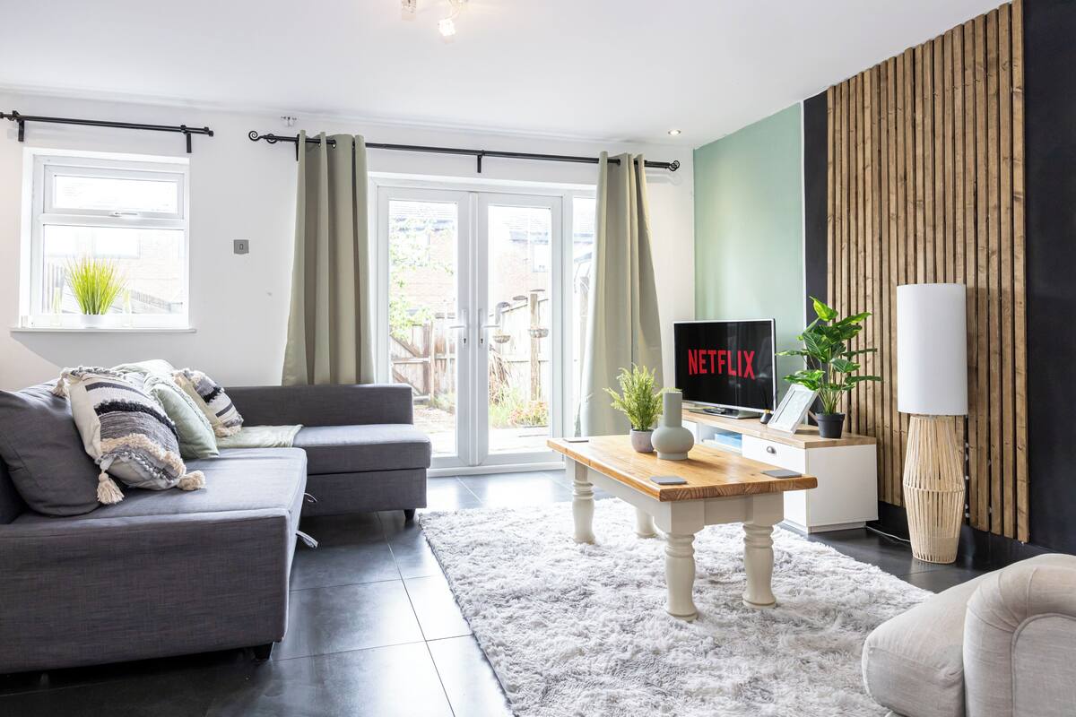 A modern living room with a grey sofa, a wooden coffee table, and a TV displaying 'NETFLIX'.