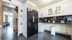 A modern kitchen with a black refrigerator, white cabinets, and a tiled backsplash. - Relaxing 4BR Near City Centre  (Salford)