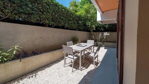 An outdoor patio with a table and chairs, surrounded by a low wall and dense foliage. - Residence City Retreat (Rodos)