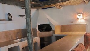 A rustic outdoor kitchen area with a built-in grill, a sink, and a seating area under a thatched roof. - A corner of paradise, surrounded by a majestic olive grove, 5 minutes from the beach. (Midoun)