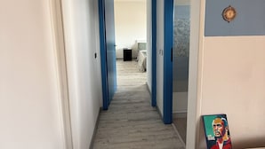 A hallway with blue doors leading to a bedroom. - Daniel Apartment (Unknown)