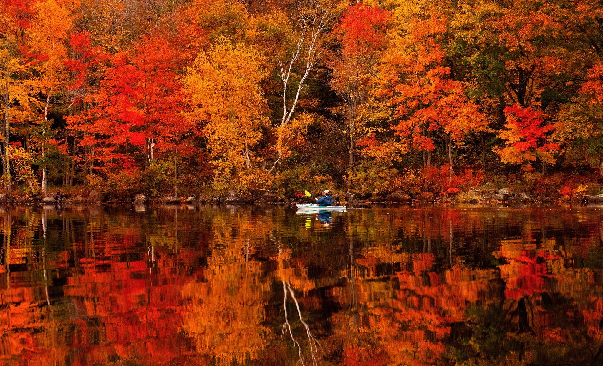 A calm lake surrounded by autumn trees reflecting vibrant colors.