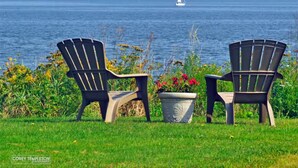 Two Adirondack chairs facing a body of water with a sailboat in the distance. - Beautiful Back Cove Area/ "Maine the Way Life Should Be" (Portland)