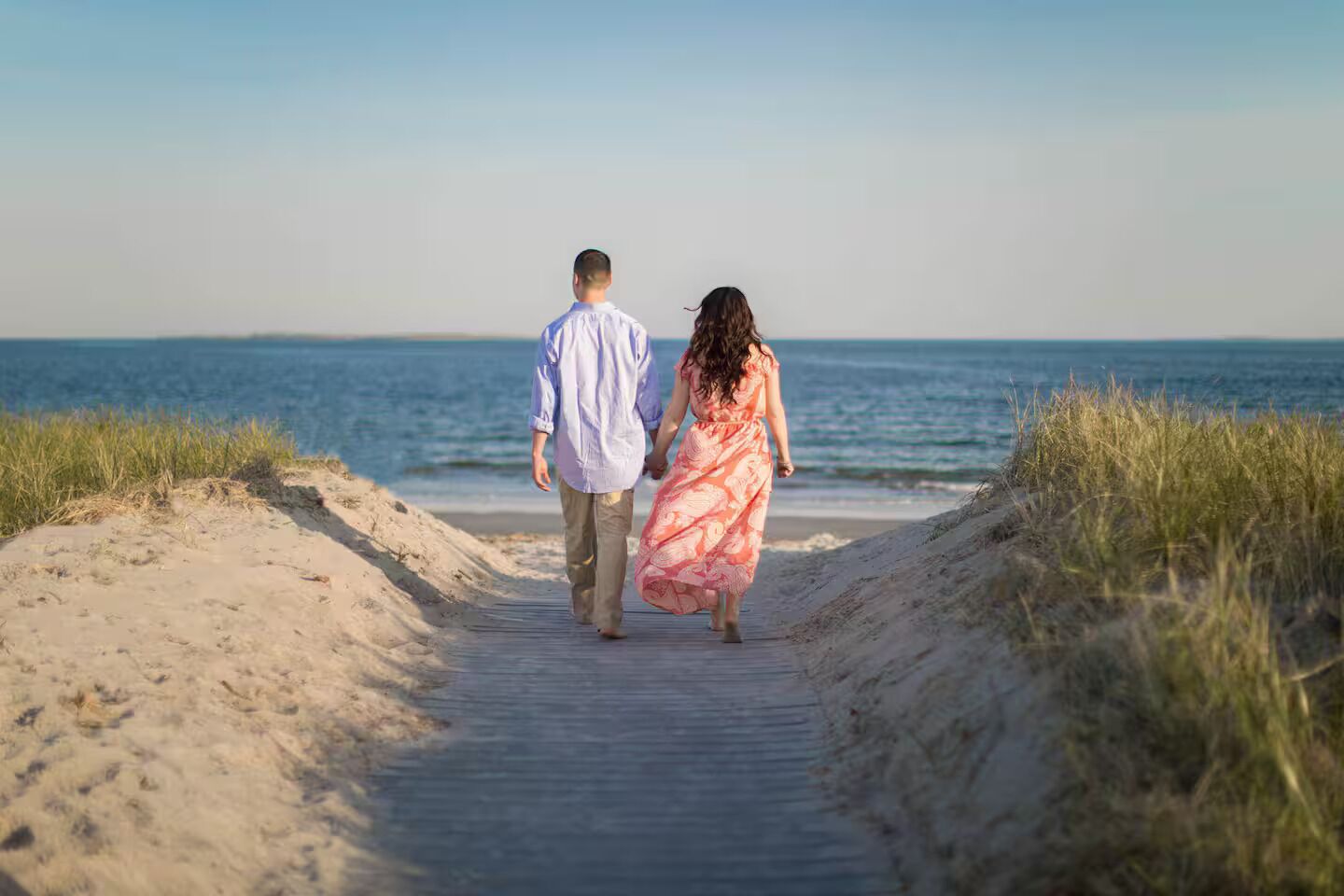 Un couple se promène sur un sentier sablonneux au bord de la plage.