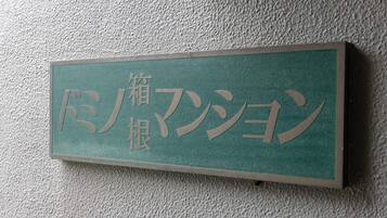 A rectangular sign with Japanese characters on a textured wall.
