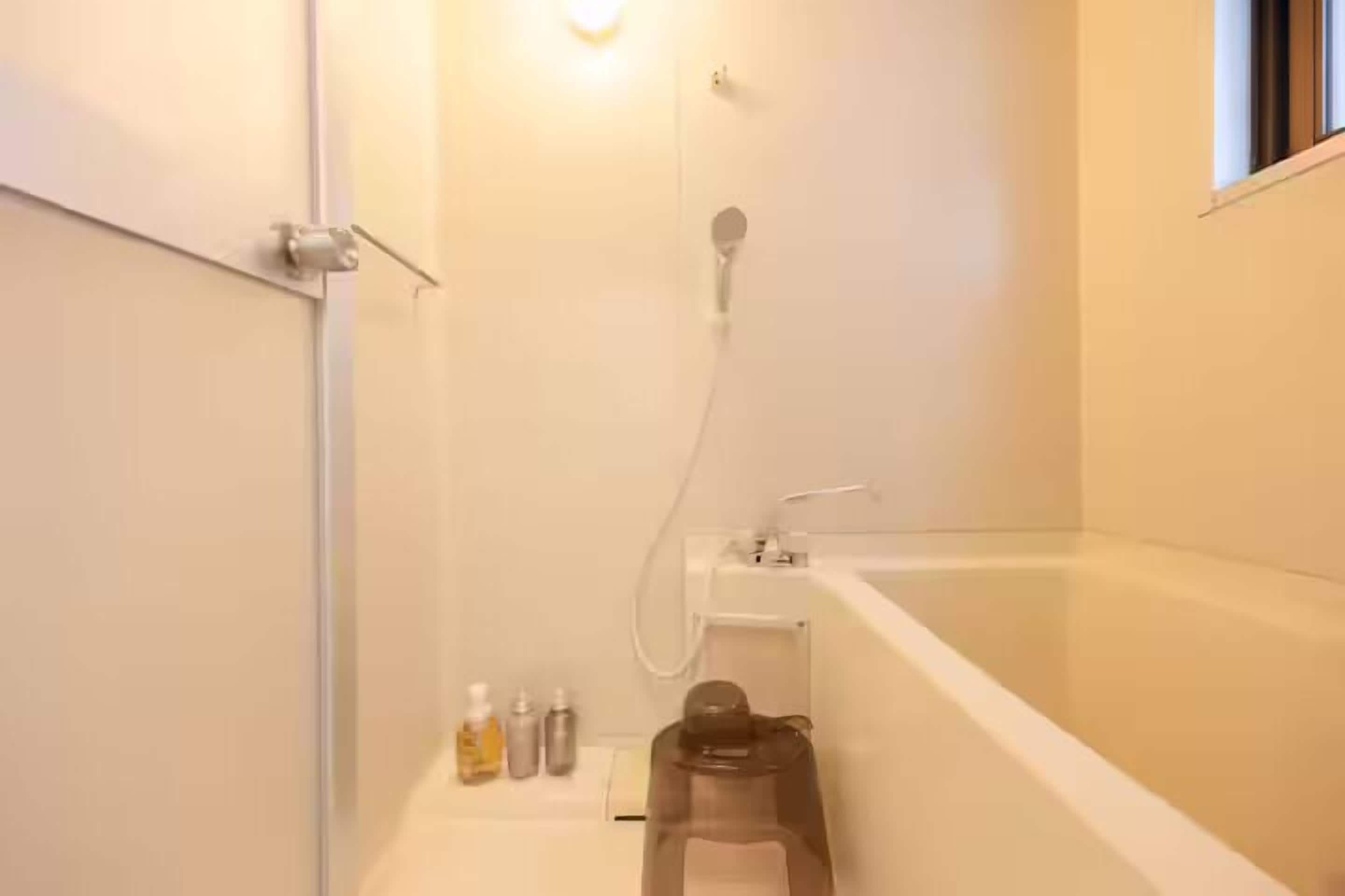 Une salle de bain avec une baignoire, une douche et des toilettes. On y trouve des articles de toilette sur le comptoir.