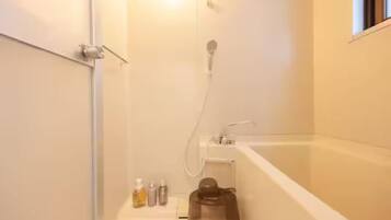 Une salle de bain avec une baignoire, une douche et des toilettes. On y trouve des articles de toilette sur le comptoir.