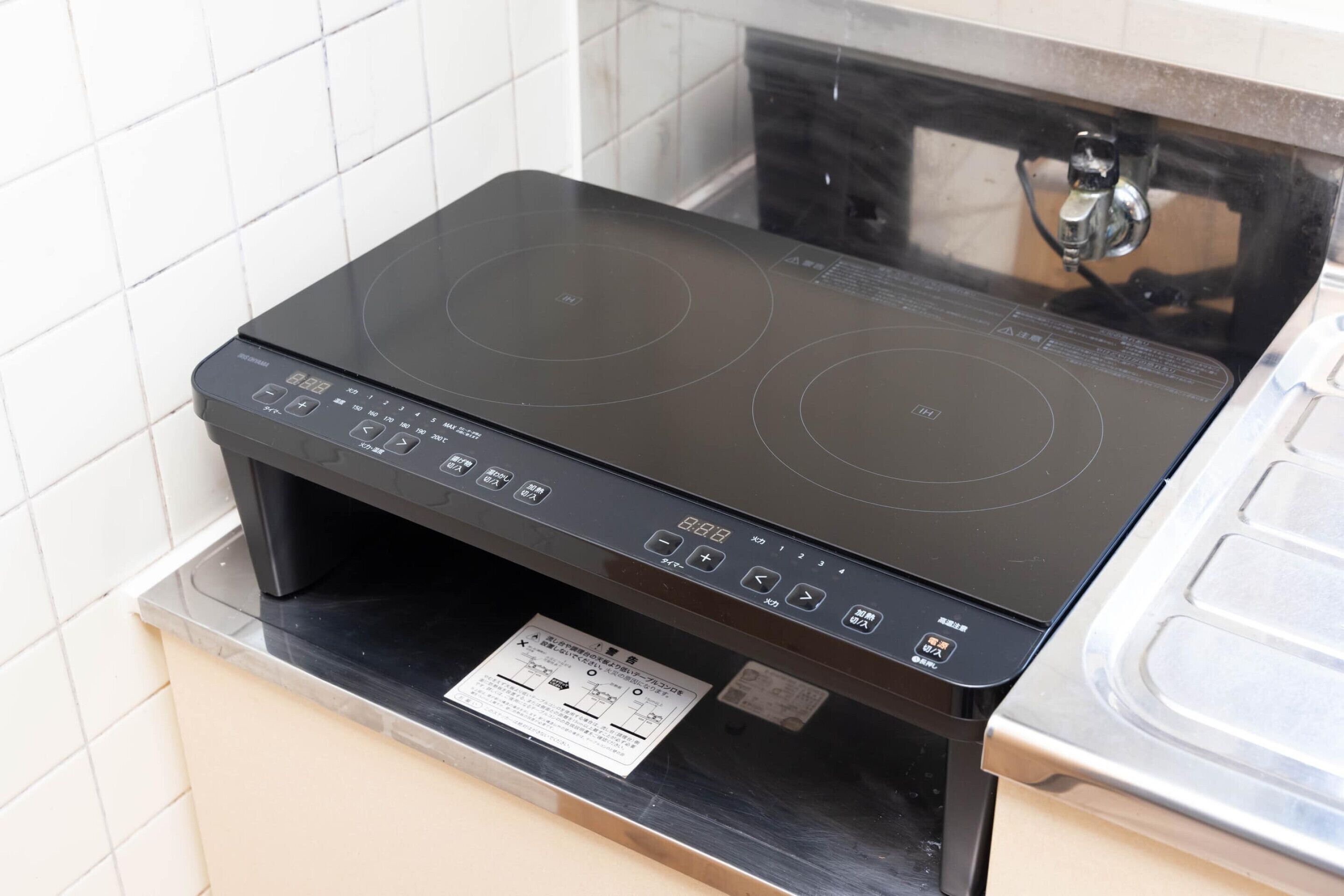 Una placa d'inducció negra amb un panell de control i una etiqueta d'instruccions de seguretat.