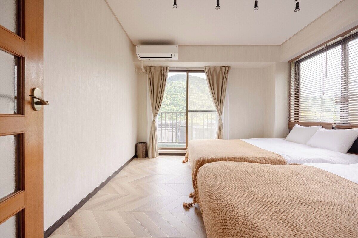 Habitación de hotel con dos camas, una puerta corrediza, un aire acondicionado y vistas a un balcón.