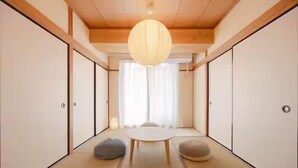 A traditional Japanese room with tatami flooring, a low table, and sliding doors.