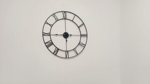 Ein Essbereich mit einem runden Tisch, vier Stühlen und einer Wanduhr.
